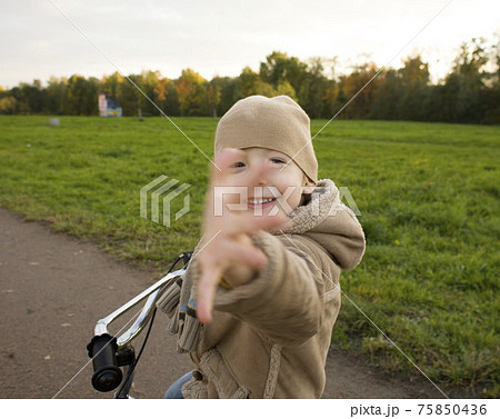 little cute real boy on bicycle emotional smiling close up outside in green amusement park little cute real boy on bicycle emotional smiling close up outside in green amusement park 75850436