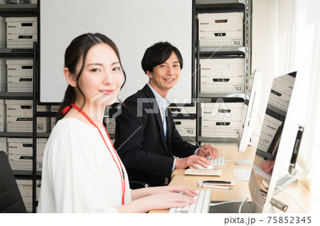 パソコンに向かって仕事する男性と女性の二人の社員 75852345