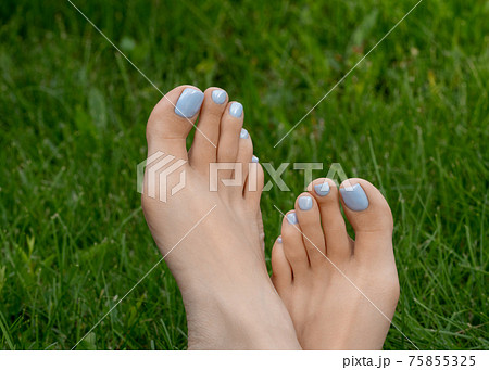 Female beautiful bare feet with fresh blue creative pedicure on green grass outdoor in summer, close up, selective focus. Female beautiful bare feet with fresh blue creative pedicure on green grass outdoor in summer, close up, selective focus. 75855325