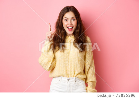 Young excited woman in stylish outfit, raising finger up, pitching an idea, saying suggestion, ahve interesting plan, standing over pink background 75855596