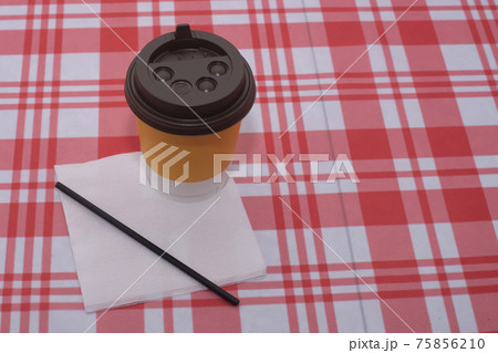 Yellow disposable glass of coffee with a straw and a napkin. 75856210
