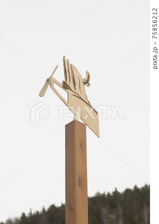 Wooden weather vane with a propeller on a wooden post. 75856212