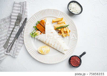 Tortilla roll with fish fingers, cheese and vegetables, on plate, on white background, top view flat lay , with copyspace and space for text Tortilla roll with fish fingers, cheese and vegetables, on plate, on white background, top view flat lay , with copyspace and space for text 75856355