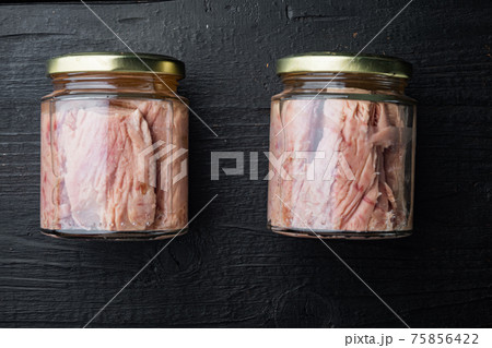 Tuna fillet in glass jar, on black wooden background, flat lay 75856422