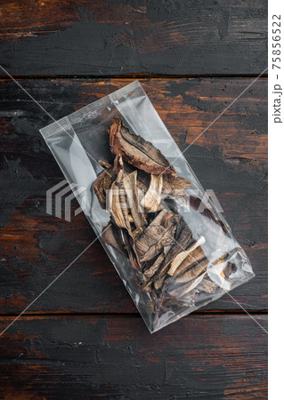 Dried porcini mushrooms, on old dark wooden table background, in plastic pack, top view flat lay Dried porcini mushrooms, on old dark wooden table background, in plastic pack, top view flat lay 75856522