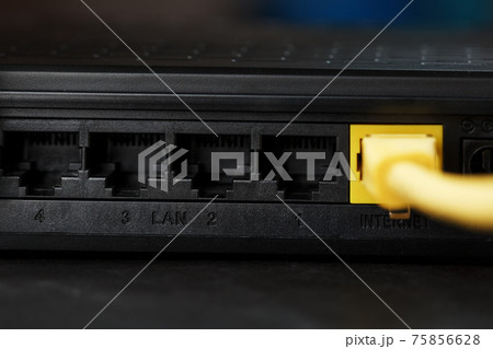 Wireless modem router with yellow cable and LAN port for connection on a black background. Wireless modem router with yellow cable and LAN port for connection on a black background. 75856628