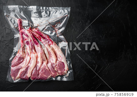Vacuum sealed fresh lamb chops for sous vide, on black stone background, top view flat lay , with copyspace and space for text 75856919