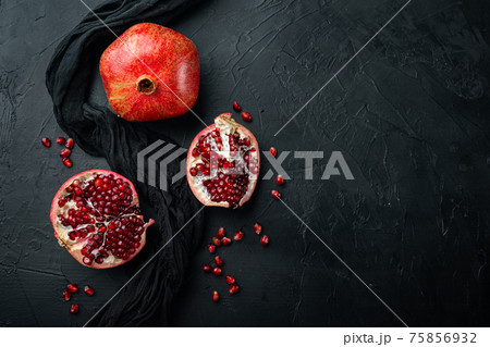 Ripe pomegranate with fresh juicy seeds, on black textured background, flat lay with space for text 75856932