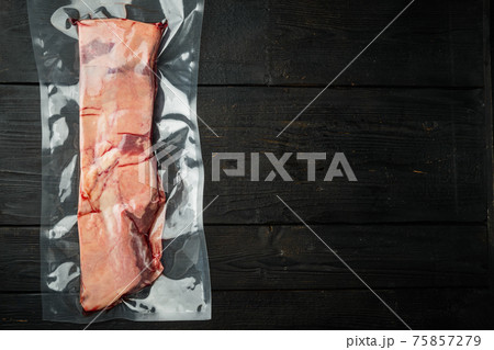 Vacuum packed meat Beef short rib, on black wooden table background, top view flat lay , with copyspace and space for text 75857279