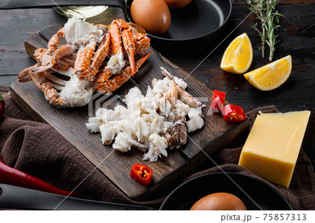Spanish or Thai omelette ingredient, fresh red chilli, brown and white crabmeat, lemon, Cheddar cheese, eggs, on dark wooden background 75857313