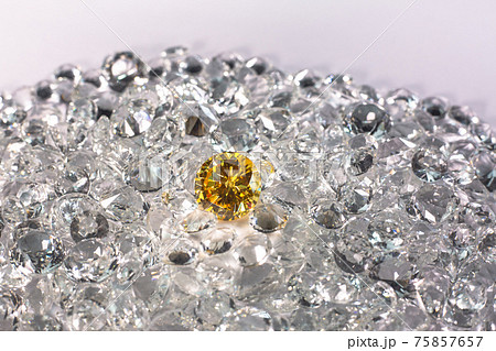 Yellow sapphire diamond on a pile of white diamonds. Yellow sapphire diamond on a pile of white diamonds. 75857657