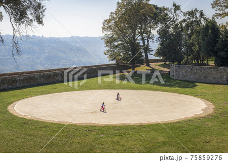 Park with round playground and children on bicycles in Orvieto, Umbria, Italy 75859276
