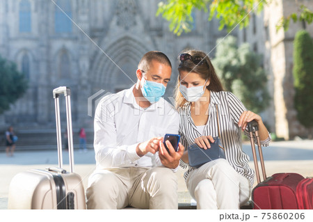 Couple of travelers in face masks reading about sights in smartphone 75860206