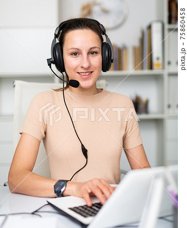 Smiling female operator talking with customer using headset at office 75860458