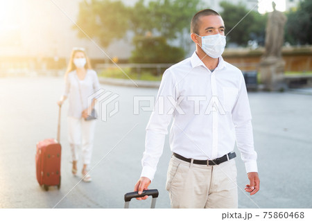 Man in face mask walking with baggage through city Man in face mask walking with baggage through city 75860468