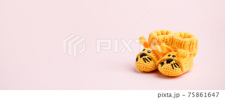 Cute yellow newborn baby shoes with funny bunny rabbit decoration over pink background. Baby shower, birthday, invitation or greeting card idea, copy space, banner, header. Handmade cloth 75861647