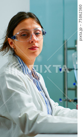 Portrait of tired scientist trying to smile at camera 75862360