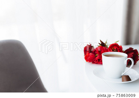 Bouquet of red tulips on table and white coffee cup. Concept for greeting card Bouquet of red tulips on table and white coffee cup. Concept for greeting card 75863009