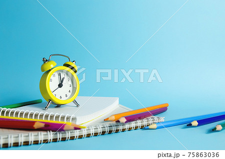 Mechanical alarm clock, notebook, pencils on the blue background 75863036