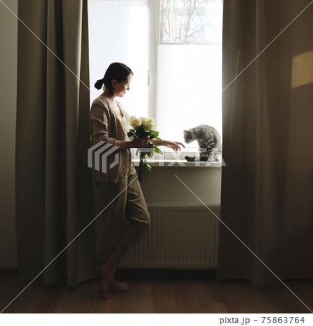 Indoor portrait of young woman playing with cat at home 75863764