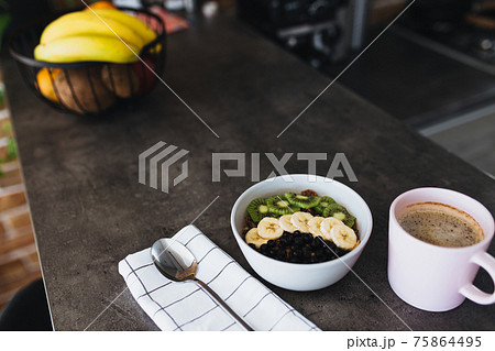 Pink coffee cup, bowl with chopped fruits and blueberries, spoon in kitchen 75864495