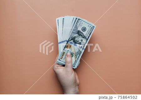 Bundle of dollars in hand on beige background 75864502