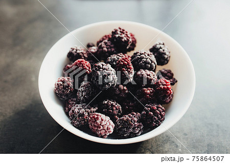 Frozen blackberries in a bowl on the table. Blurred background 75864507