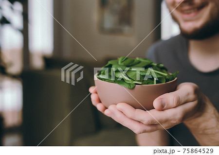 Man holding fresh green salad leaves of spinach, blurred background Man holding fresh green salad leaves of spinach, blurred background 75864529