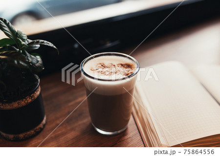 Cup of coffee, notebook at table in cafe. Blurred background 75864556