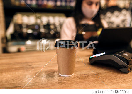 Buying a cup of coffee in a cafe, barista, NFC terminal. Blurred background Buying a cup of coffee in a cafe, barista, NFC terminal. Blurred background 75864559