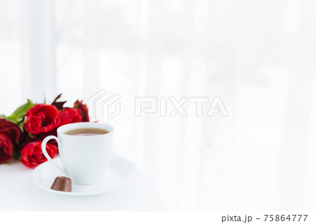 Bouquet of red tulips on table and white coffee cup. Concept for greeting card Bouquet of red tulips on table and white coffee cup. Concept for greeting card 75864777