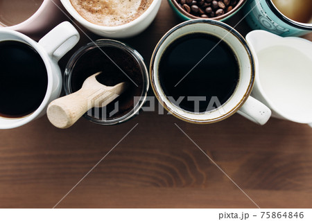 Multiple coffee cups, milk, beans and ground coffee in jar on wooden background Multiple coffee cups, milk, beans and ground coffee in jar on wooden background 75864846