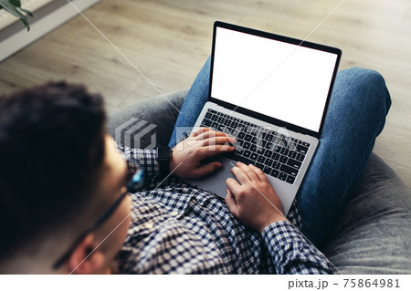 Man using laptop, wearing glasses, cushioned furniture. Blurred background 75864981