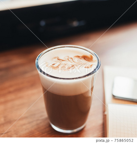 Cup of coffee, notebook at table in cafe. Blurred background Cup of coffee, notebook at table in cafe. Blurred background 75865052