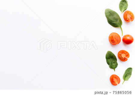 Red cherry tomatoes, green spinach leaves on white background. Healthy eating 75865056