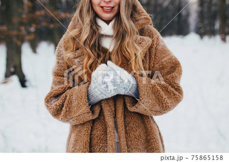 Young woman in fur coat, gloves and scarf in snowy forest. Blurred background Young woman in fur coat, gloves and scarf in snowy forest. Blurred background 75865158