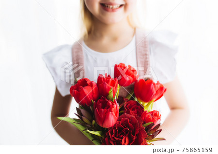 Smiling small girl holding bouquet of red tulips. Concept for greeting card Smiling small girl holding bouquet of red tulips. Concept for greeting card 75865159