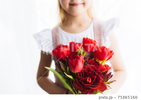 Smiling small girl holding bouquet of red tulips. Concept for greeting card Smiling small girl holding bouquet of red tulips. Concept for greeting card 75865160