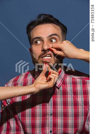 Female hands rumple young bearded handsome man on blue background Female hands rumple young bearded handsome man on blue background 75865358