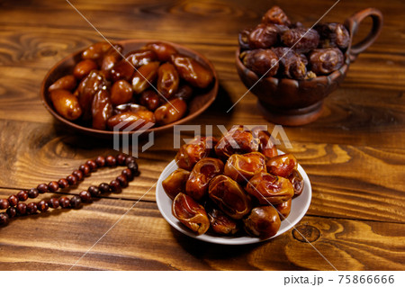 Dates fruit and rosary on wooden table Dates fruit and rosary on wooden table 75866666