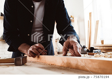 Carpenter makes pencil marks on a wood plank 75870194