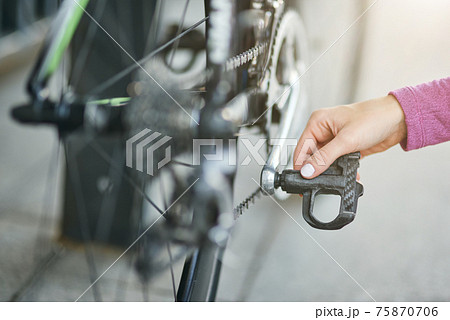 Close up shot of hand of female cyclist checking her bicycle mechanisms, sprocket and pedal on a mountain bike outdoors on a daytime Close up shot of hand of female cyclist checking her bicycle mechanisms, sprocket and pedal on a mountain bike outdoors on a daytime 75870706