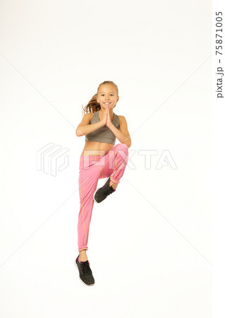 Cheerful female kid in sportswear jumping in studio Cheerful female kid in sportswear jumping in studio 75871005