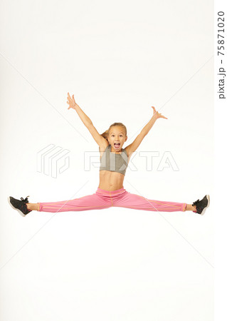 Cheerful sporty girl jumping and doing splits in the air Cheerful sporty girl jumping and doing splits in the air 75871020