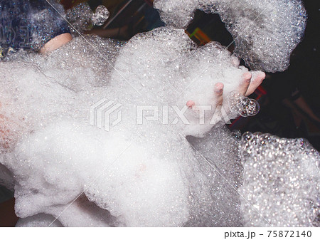 Lots of soap suds in the hands of a man at a foam party in a nightclub background Lots of soap suds in the hands of a man at a foam party in a nightclub background 75872140