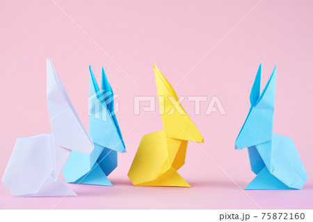 Paper colorful origami Esater rabbits on a pink background. Easter celebration concept Paper colorful origami Esater rabbits on a pink background. Easter celebration concept 75872160