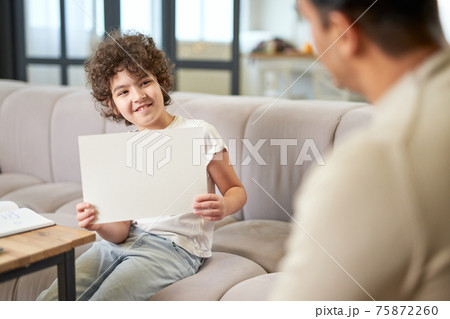 Happy latin boy showing the drawing to his dad while spending time with his father, playing in the living room at home 75872260