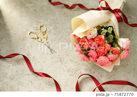 赤いリボンで結ばれたバラとカーネーションの花束にハサミの写真素材