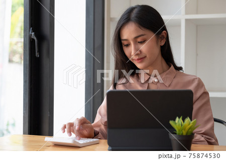 Shot of accountant working on desk office with using a calculator to calculate the numbers, finance accounting concept. 75874530