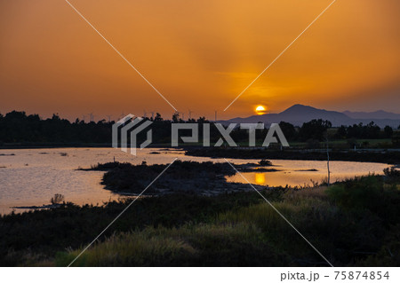 Sunset at the Larnaca salt lake witht he setting sun and wind turbines in the distance 75874854